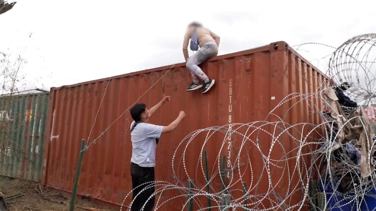 <i>CNN</i><br/>Venezuelan couple Kevin and Vanessa climb over a shipping container at the US-Mexico border. A portion of this image has been blurred by CNN to protect Vanessa's identity.