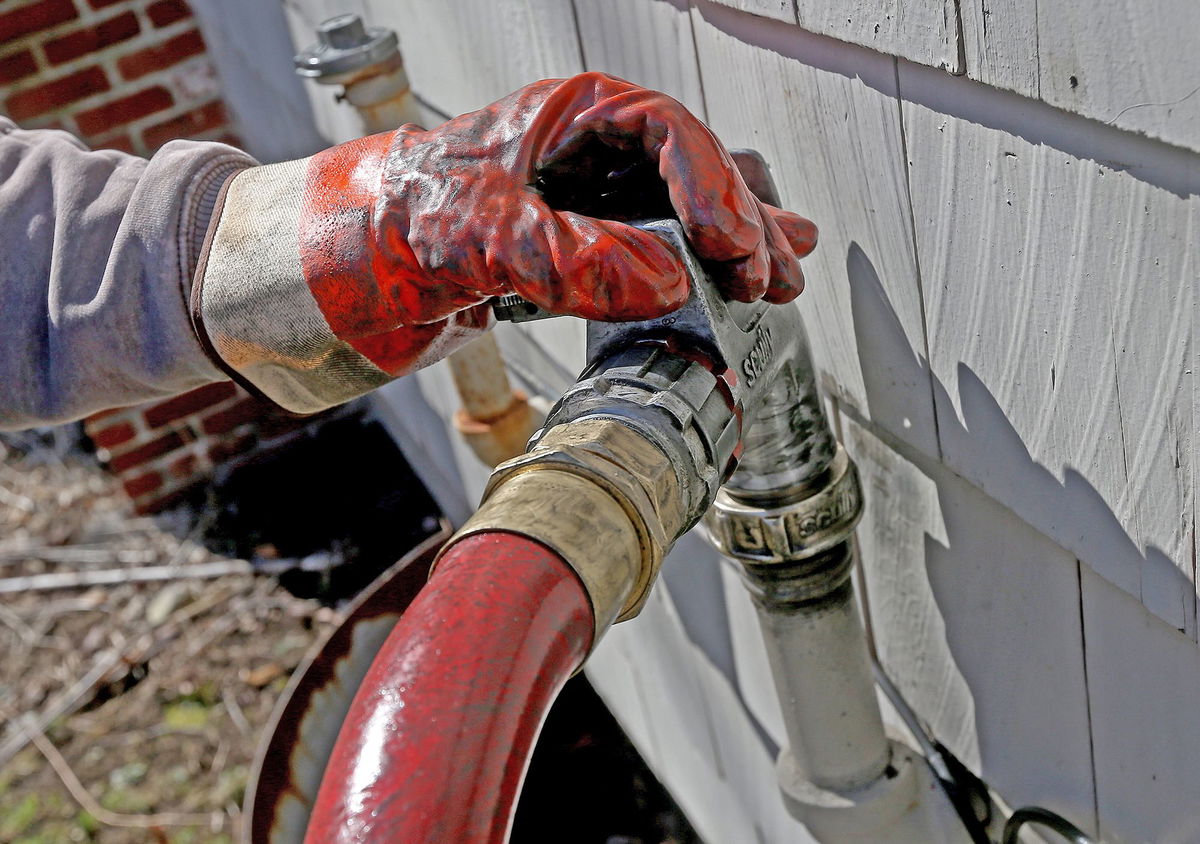 <i>Matt Stone/MediaNews Group/Boston Herald/Getty Images</i><br/>Corey Carlson of Anderson Fuel fills a house with home heating oil which has risen to over $5.00 a gallon on March 8