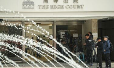 Media members stand outside the High Court where a court hearing on property developer China Evergrande Group is held