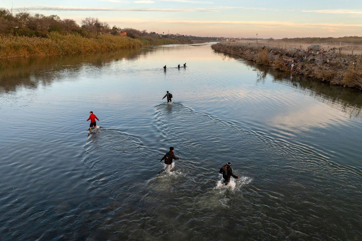 <i>John Moore/Getty Images</i><br/>Immigrants wade across the Rio Grande while crossing Sunday from Mexico to Eagle Pass