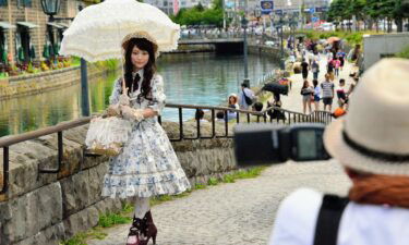 A young woman sporting Lolita fashion poses for photographs along the Otaru Canal in the background on June 29