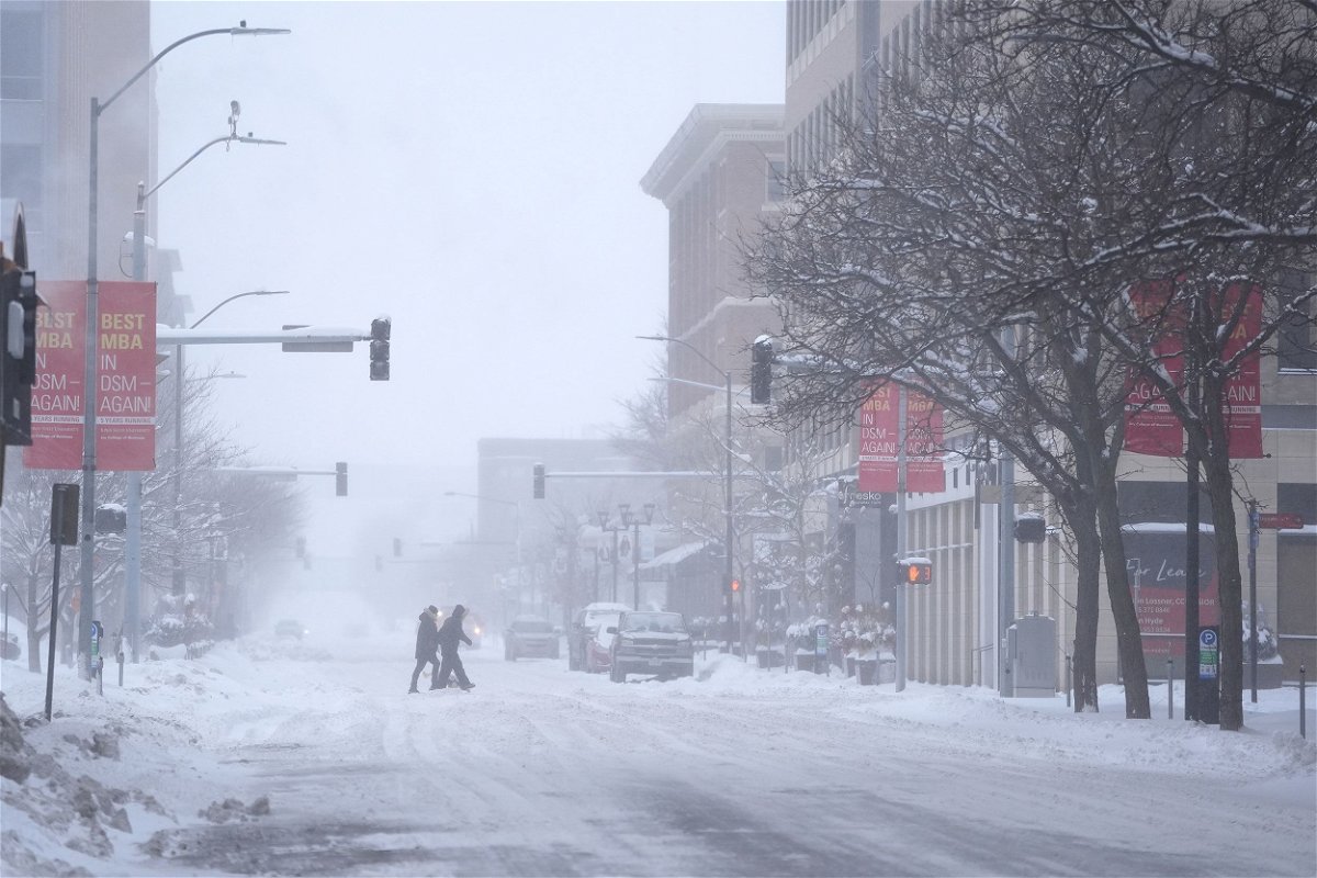 <i>Abbie Parr/AP</i><br/>Pedestrians cross the street in snowy conditions on Friday