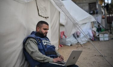 A press member is seen sitting next to a tent as he tries to connect to the internet while he and his colleagues in Gaza face high risks trying to cover the Israel-Gaza war on January 14 in Rafah