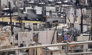 Two people examine a burned house on August 13