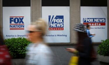 People walk past Fox News posters on the exterior of the Fox News headquarters building in New York City