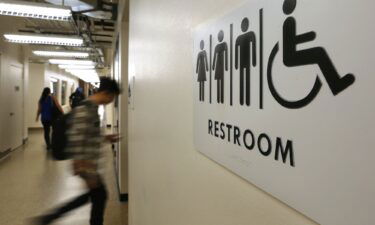 Students pass by a sign for a unisex bathroom next to the men's and women's restroomS at the University of Houston Downtown