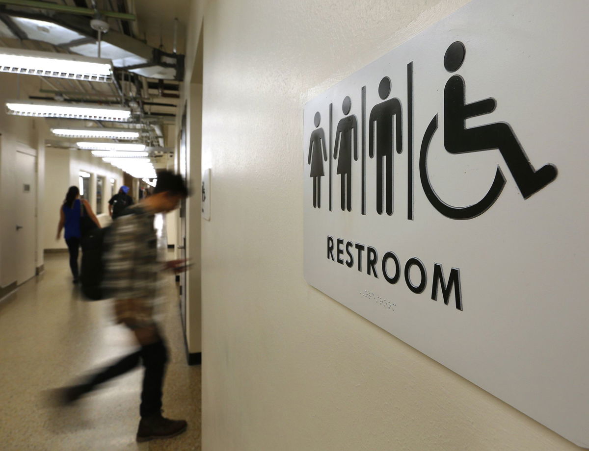 <i>Mark Mulligan/Houston Chronicle/Getty Images</i><br/>Students pass by a sign for a unisex bathroom next to the men's and women's restroomS at the University of Houston Downtown