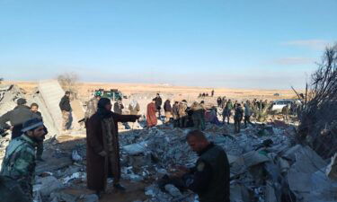 Residents gather around destroyed buildings after US warplanes carried out an airstrike on the headquarters of Hashd al-Shaabi in Al-Qaim city of Anbar