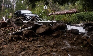 A car sits on top of a pile of debris during a rain storm in Studio City