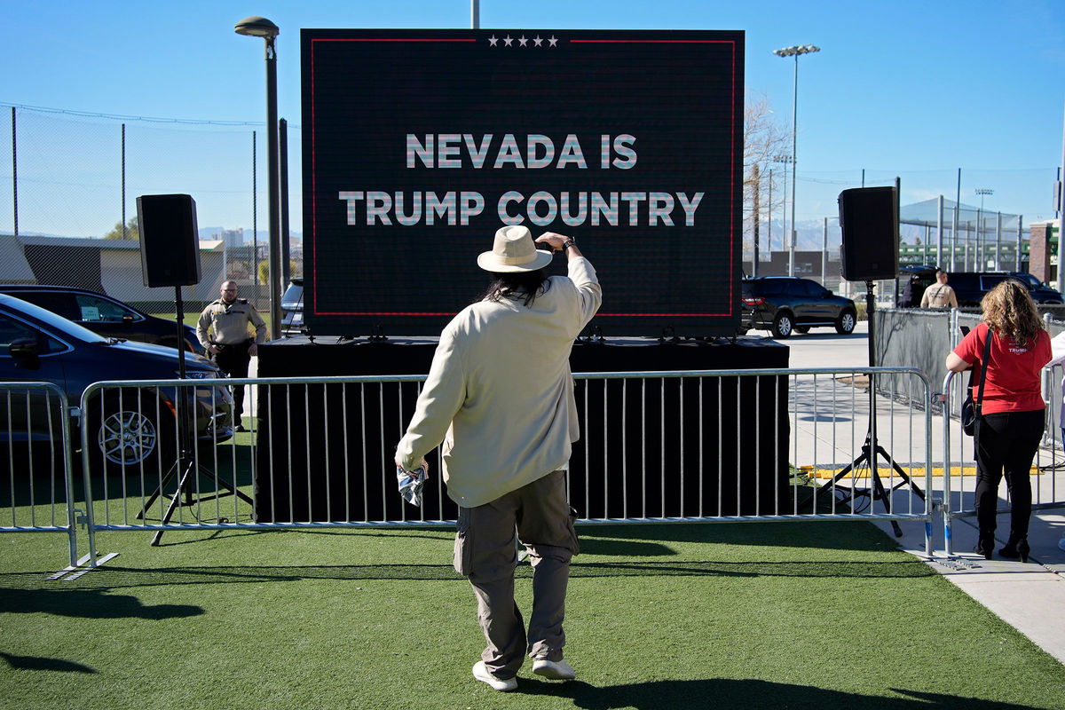 <i>John Locher/AP</i><br/>A person takes a picture of a screen before former President Donald Trump speaks at a campaign event in Las Vegas on January 27