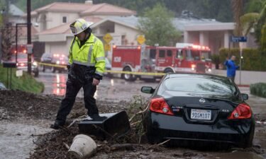 A firefighter walks near a vehicle stranded in mud and rock during a storm in Los Angeles on February 5.