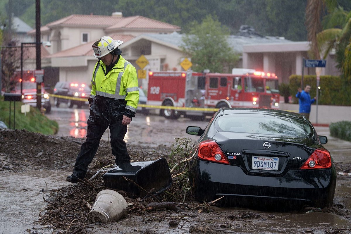 <i>Eric Thayer/Bloomberg/Getty Images</i><br/>A firefighter walks near a vehicle stranded in mud and rock during a storm in Los Angeles on February 5.