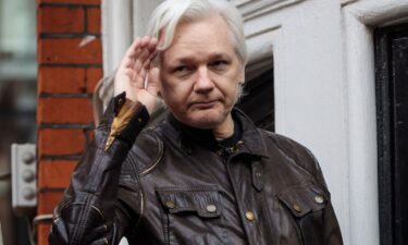 Julian Assange gestures while speaking to the media from the balcony of the Ecuadorian Embassy on May 19