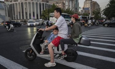 A boy riding with his parents on a scooter in Beijing