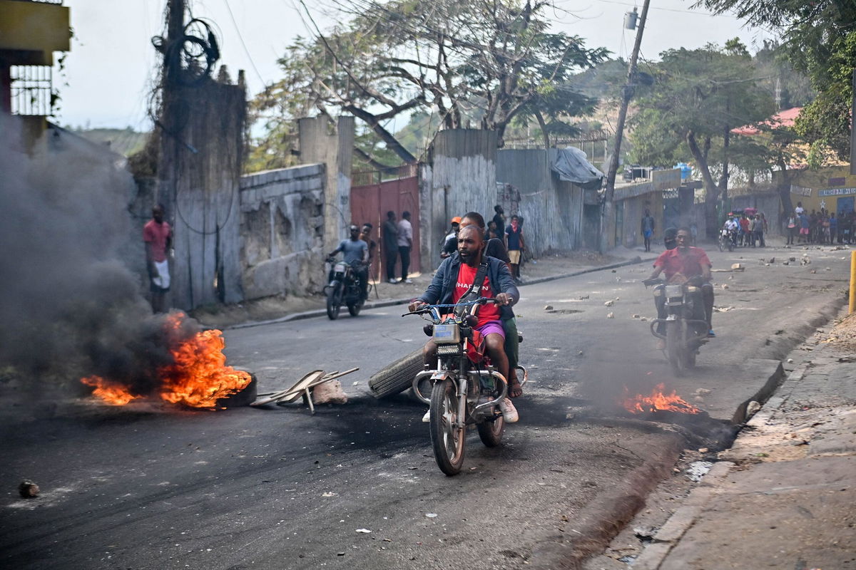 <i>Richard Pierrin/AFP/Getty Images</i><br/>Motorcyclists pass burning tires during a demonstration calling for the resignation of Prime Minister Ariel Henry