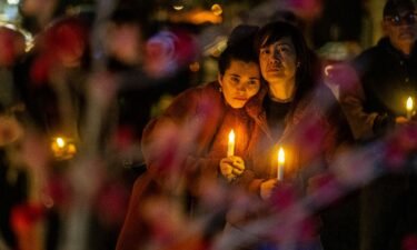 People clutch candles during a vigil on the one-year anniversary of a mass shooting on January 21