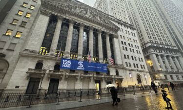 Pedestrians pass the New York Stock Exchange as snow falls on Tuesday
