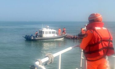 The Taiwan coast guard inspect a vessel that capsized during a chase off the coast of Kinmen island in Taiwan on Feb. 14