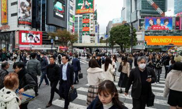 People walk past a busy crossing in Tokyo