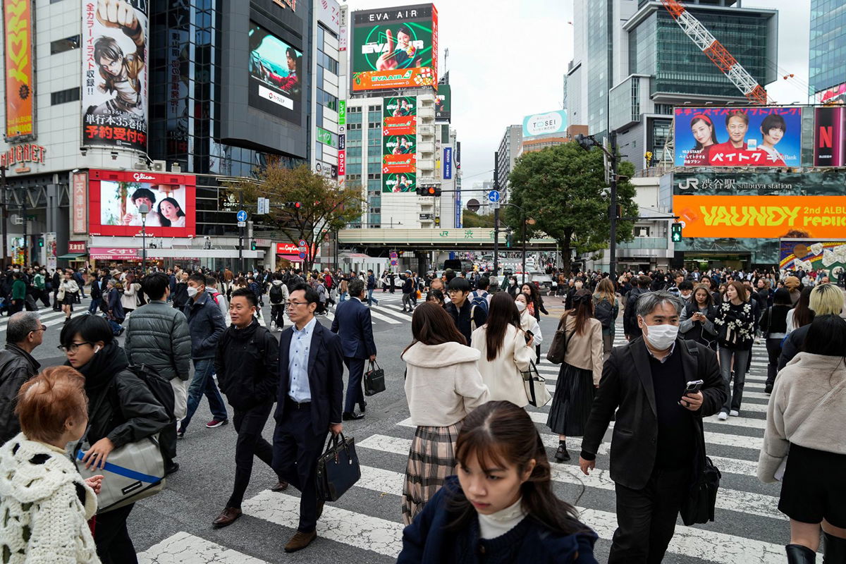 <i>Zhang Xiaoyu/Xinhua/Getty Images</i><br/>People walk past a busy crossing in Tokyo