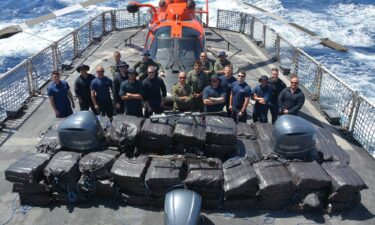 Crewmembers of the Coast Guard Cutter Alert (WMEC 630) stand behind cocaine bales seized from a drug smuggling vessel in Eastern Pacific waters on February 7. The 4