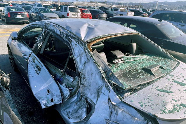 A damaged car is seen in an on-airport employee parking lot after tire debris from a Boeing 777 landed on it at San Francisco International Airport on Thursday