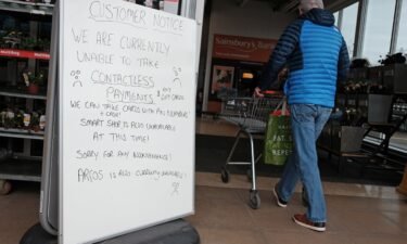 A handwritten sign outside a Sainsbury's store in Cobham informing customers of technical issues currently affecting the supermarket chain. Two of the UK's biggest supermarket chains
