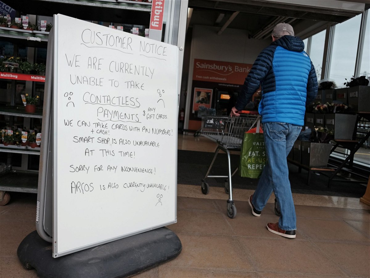 <i>Yui Mok/PA Images/Getty Images via CNN Newsource</i><br/>A handwritten sign outside a Sainsbury's store in Cobham informing customers of technical issues currently affecting the supermarket chain. Two of the UK's biggest supermarket chains