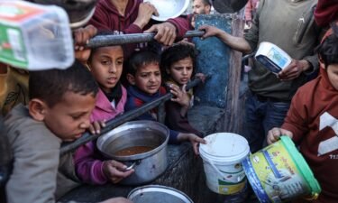 Displaced Palestinians gather to collect food donated by a charitable youth group before breakfast
