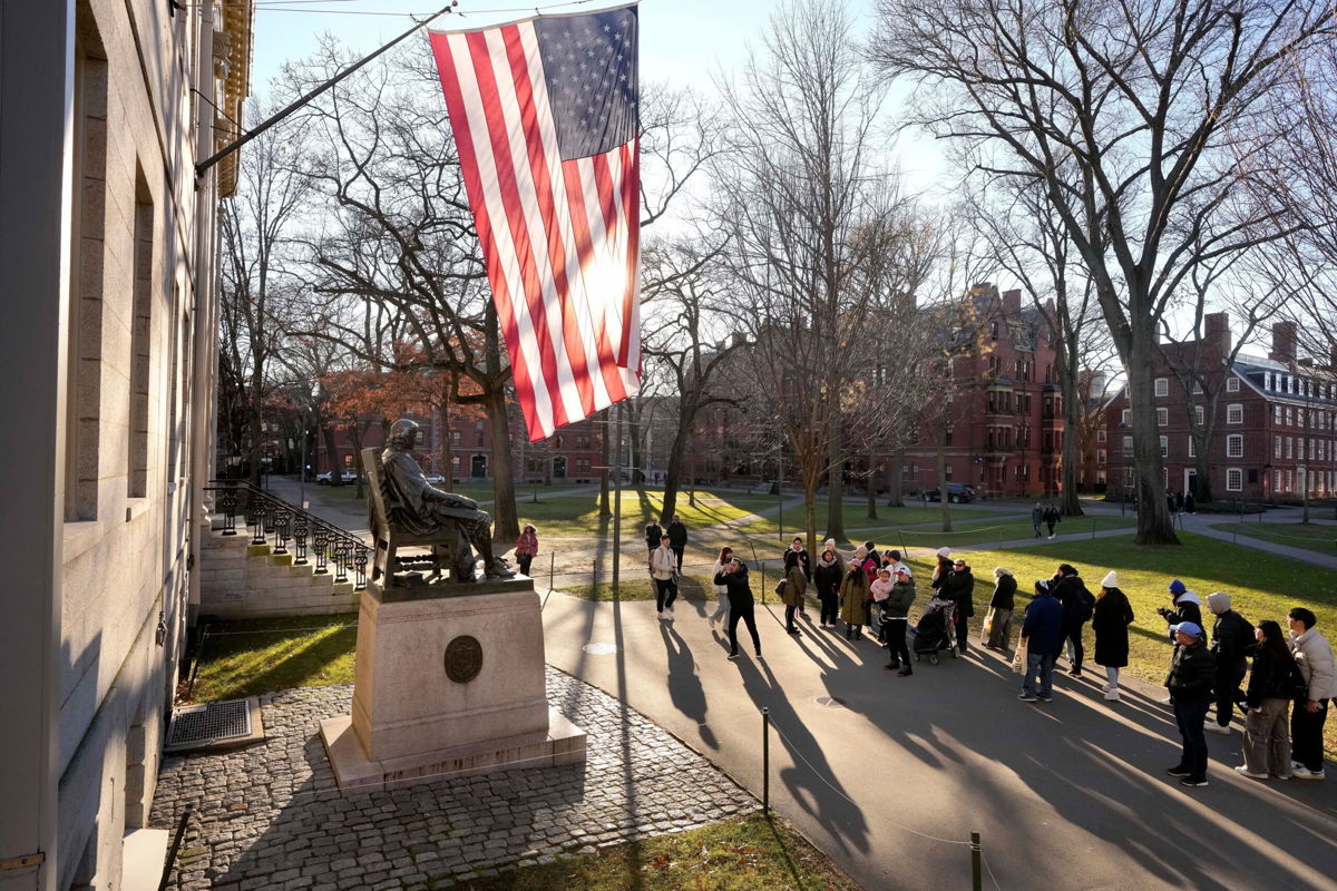 <i>Steven Senne/AP via CNN Newsource</i><br/>People take photographs near a John Harvard statue