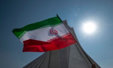 An Iranian waves an Iranian flag in front of the Azadi (Freedom) monument in western Tehran