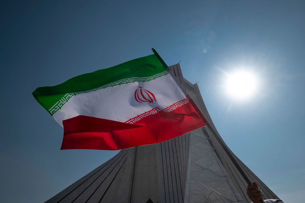 <i>Morteza Nikoubazl/NurPhoto/Getty Images via CNN Newsource</i><br/>An Iranian waves an Iranian flag in front of the Azadi (Freedom) monument in western Tehran