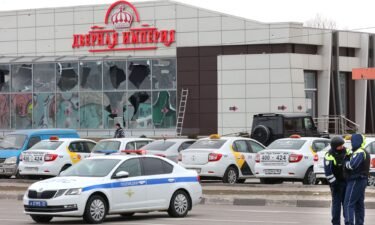Police stand guard in front of a damaged store amid air strikes on Belgorod