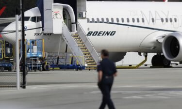 A worker walks next to a Boeing 737 MAX 8 airplane parked at Boeing Field in Seattle