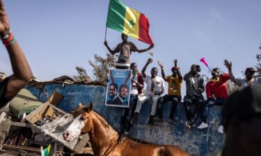 A supporter of the coalition of anti-establishment candidates holds a Senegalese flag as they sit on top of a wall during a campaign rally in Dakar on March 10.