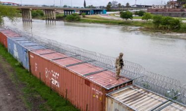 A Texas National Guard soldier stands atop a barrier of shipping containers and razor wire while guarding the US-Mexico border on March 17