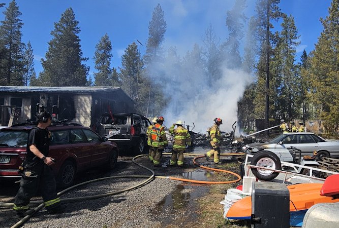 Fire that destroyed La Pine garage-shop Monday heavily damaged home.; vehicles, was spreading to wildland