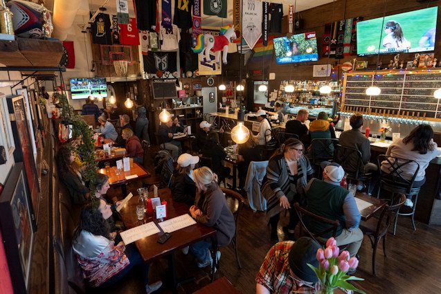 Customers eat and watch college women's lacrosse and beach volleyball matches on big-screen TVs at The Sports Bra sports bar on Wednesday, April 24, in Portland.