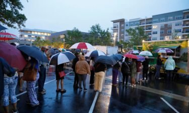 Attendees of the Taste of Mississippi event wait in line in the rain in Jackson