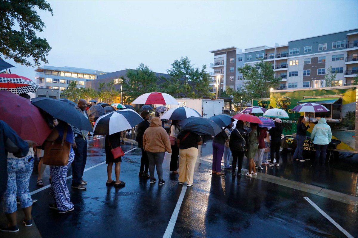 Attendees of the Taste of Mississippi event wait in line in the rain in Jackson
