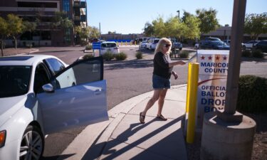 A woman drops her ballot for the upcoming midterm elections in the drop box near the Maricopa County Juvenile Court Center in Mesa