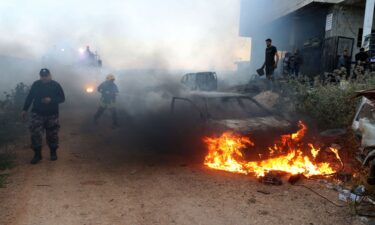 Israeli settlers wearing headscarves are seen near billowing smoke.