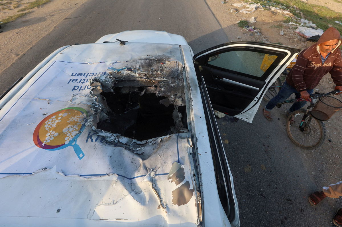 <i>Ahmed Zakot/Reuters via CNN Newsource</i><br/>A Palestinian man rides a bicycle past a damaged vehicle where employees from the World Central Kitchen were killed in an Israeli airstrike