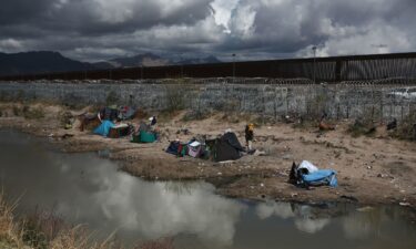 Migrants build makeshift tents with blankets to protect themselves from the cold as an American helicopter guards the border in Ciudad Juarez