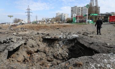 A man walks past a crater after Russian missile strikes on Kharkiv