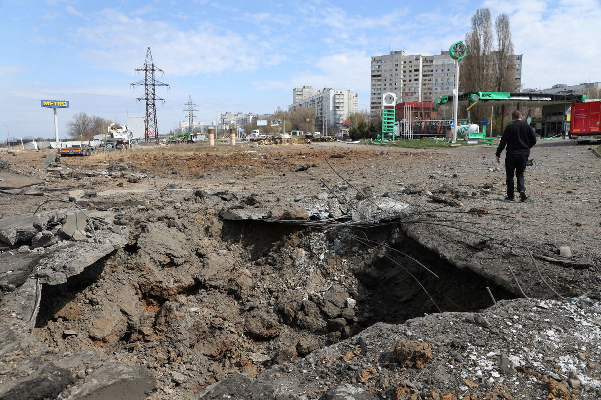 <i>Anton Shtuka/AFP/Getty Images via CNN Newsource</i><br/>A man walks past a crater after Russian missile strikes on Kharkiv