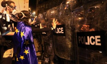 A protester draped in an European Union flag confronts riot police in Tbilisi