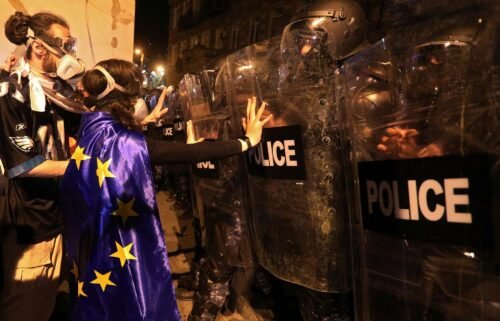 A protester draped in an European Union flag confronts riot police in Tbilisi