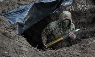 A Ukrainian soldier holds an artillery shell as he prepares to fire a howitzer towards Russian troops near the town of Kreminna