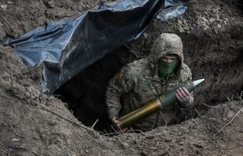 A Ukrainian soldier holds an artillery shell as he prepares to fire a howitzer towards Russian troops near the town of Kreminna